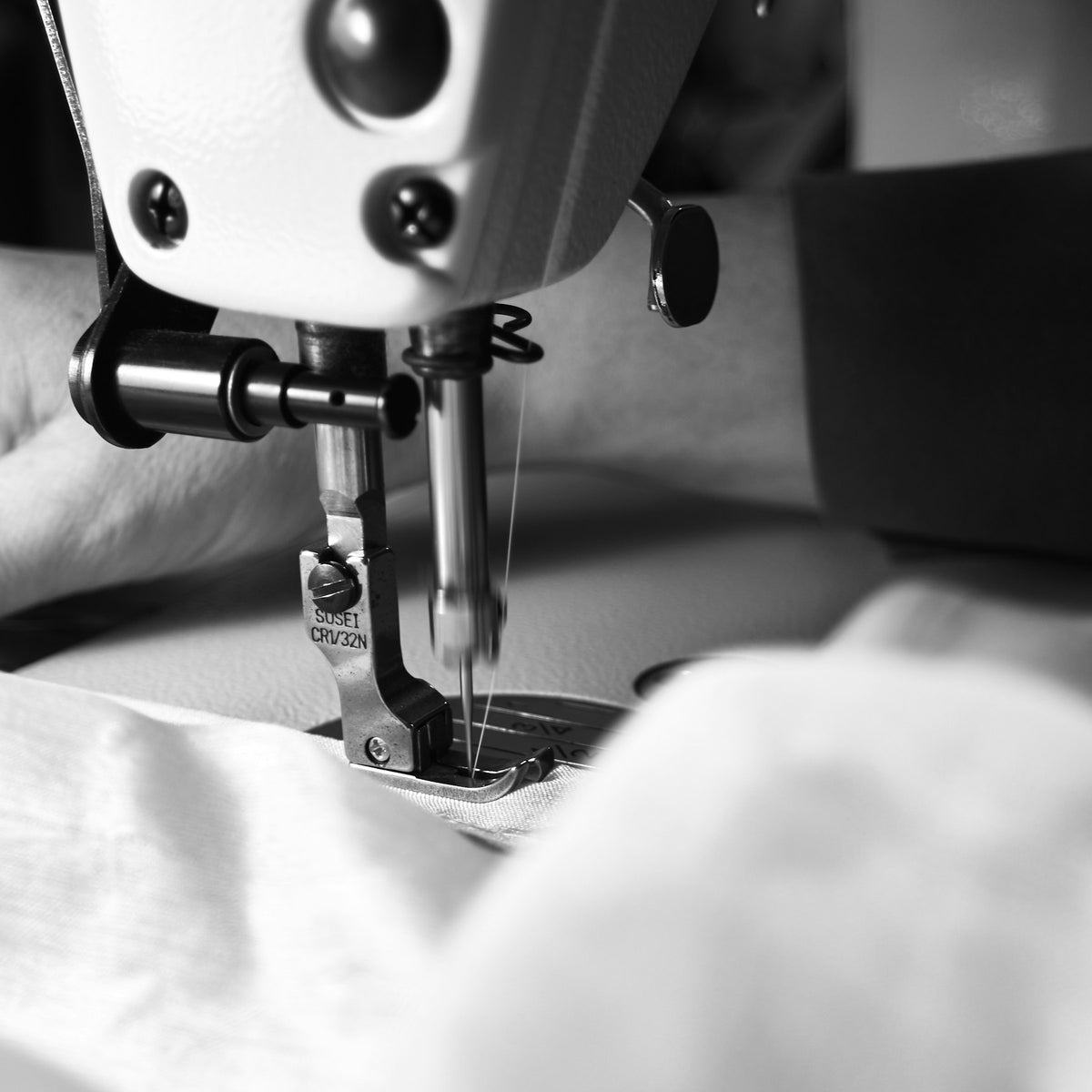 Nähmaschine bei der Arbeit an hellem Stoff